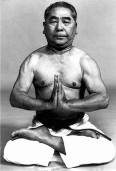 an old man sitting in the middle of a yoga pose with his hands clasped up