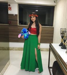 a woman in a long green skirt holding a stuffed animal and smiling at the camera