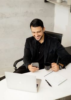 a man sitting at a desk with a laptop and cell phone