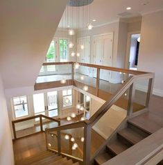 a staircase with lights hanging from it's sides in a large room that has hardwood floors and white walls