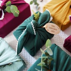 presents wrapped in green and brown paper with wooden tags on them sitting on a table