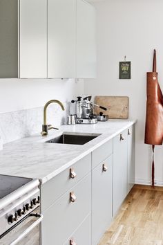 a kitchen with marble counter tops and stainless steel oven hoods, white cabinets and wooden flooring