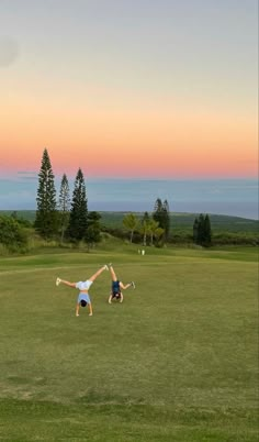 two people standing in the middle of a field with their arms up and one person holding a tennis racquet