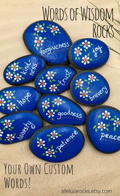 blue rocks with words painted on them and flowers in the middle, surrounded by grass