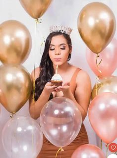 a woman wearing a tiara and holding a cupcake surrounded by balloons