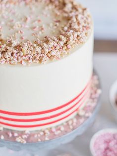 a white cake with sprinkles on it sitting on top of a table