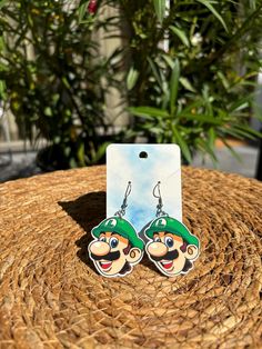 the mario brothers earrings are on display in front of some potted plants and trees