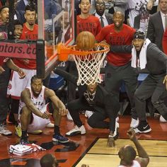 a group of men playing basketball on top of a court with people watching them from the sidelines