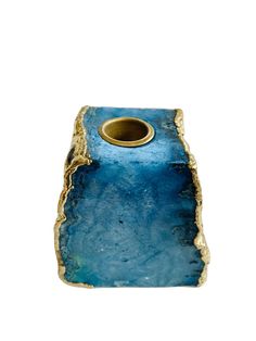 a blue and gold vase sitting on top of a white surface with a small hole in the middle