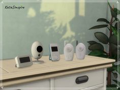 there are five electronic devices on top of the dresser in front of a potted plant