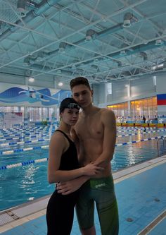 a man and woman standing next to each other in front of a large swimming pool