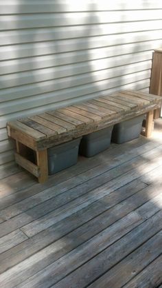 a wooden bench sitting on top of a wooden floor next to a white wall and two planters