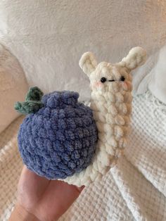 a hand holding a small crocheted animal with a blue ball on it's back