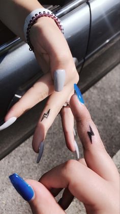 two people with matching tattoos on their fingers are touching each other's hands while holding onto the car door