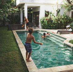 a young boy playing with a frisbee in a pool next to a house