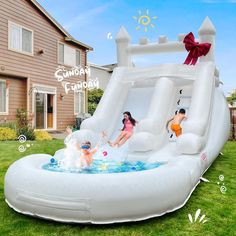 an inflatable water slide with two children playing inside it on the lawn next to a house