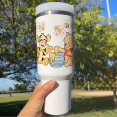 a person holding up a white cup with winnie the pooh on it