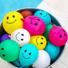 a bucket filled with lots of different colored balls next to a swimming pool or pool