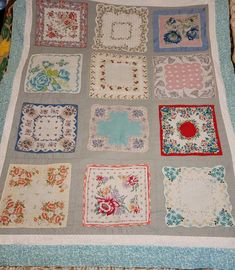 a quilted blanket with many squares and flowers on the bottom, in various colors