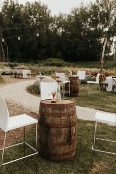 a wooden barrel sitting on top of a grass covered field next to chairs and tables