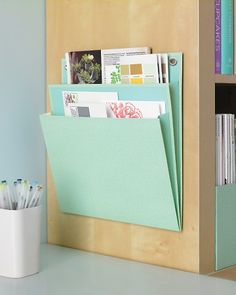 an office desk with books, pens and folders on the shelf next to it