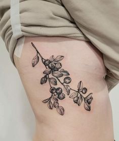 a woman's lower thigh with an olive branch tattoo on her side ribcage