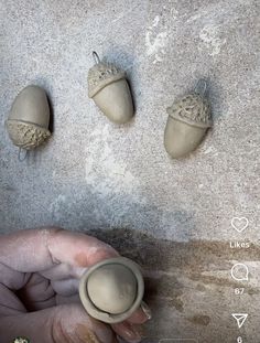 three clay acorns sitting on the ground next to a person's hand