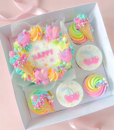 a box filled with cupcakes covered in frosting and rainbow icing on top of each other