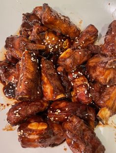 a plate full of chicken wings with sesame seeds on the top and sesame seeds on the bottom