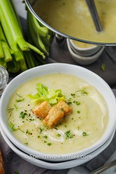 a white bowl filled with soup next to some celery and other food items