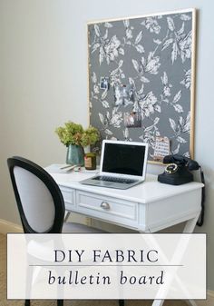 a white desk topped with a laptop computer next to a wall mounted art work area