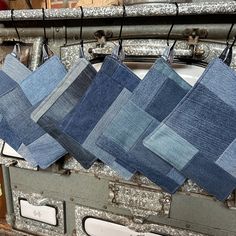 several pieces of denim hanging from hooks on a metal rack in front of a brick wall