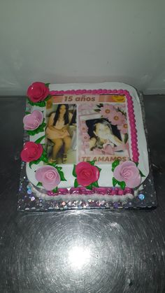 a cake with pink roses on it and two photos in the middle, sitting on a table