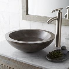 a bowl sink sitting on top of a bathroom counter next to a faucet