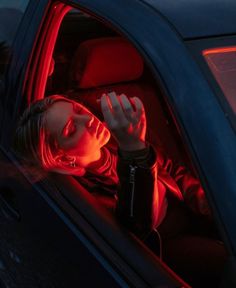 a woman sitting in the back seat of a car with her hand on her head