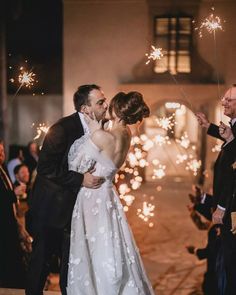 a bride and groom kissing in front of sparklers