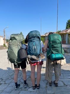 two women with backpacks are standing on the street