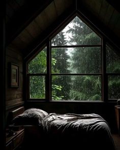 a bed sitting under a window next to a forest