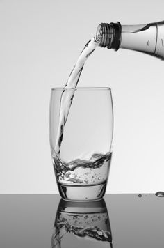 a glass filled with water being poured into it