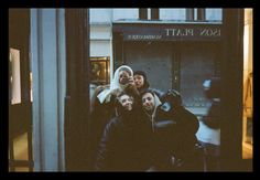 four people are standing in front of a building