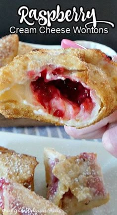 a hand holding a pastry with cream cheese wontons in the background and strawberry filling on top