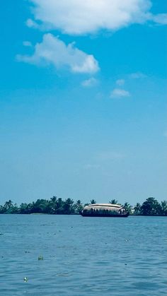 a large body of water with a boat in the middle of it and trees on both sides