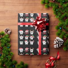 a present wrapped in black wrapping paper with red bows and reindeers on it next to christmas decorations