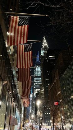 an american flag hanging from the side of a building in new york city at night