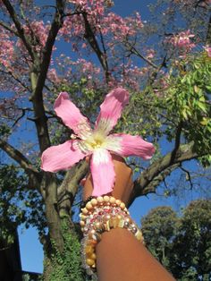 a person's arm with bracelets and a pink flower on top of it