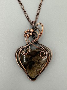 a wire wrapped necklace with a stone in the shape of a heart on a chain