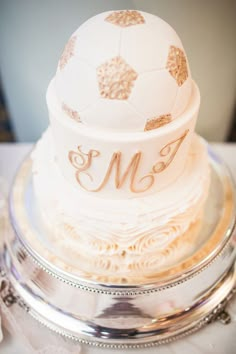 a white and gold wedding cake sitting on top of a silver platter