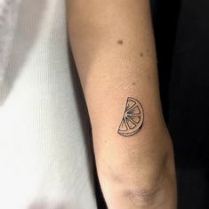 a person with a tattoo on their arm holding a piece of fruit in one hand