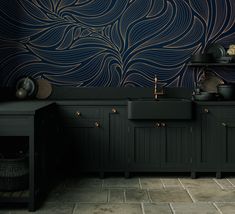 a kitchen with black cabinets and an artistic wallpaper