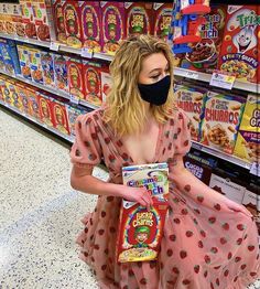 a woman wearing a face mask and holding a bag of cereal in a store aisle